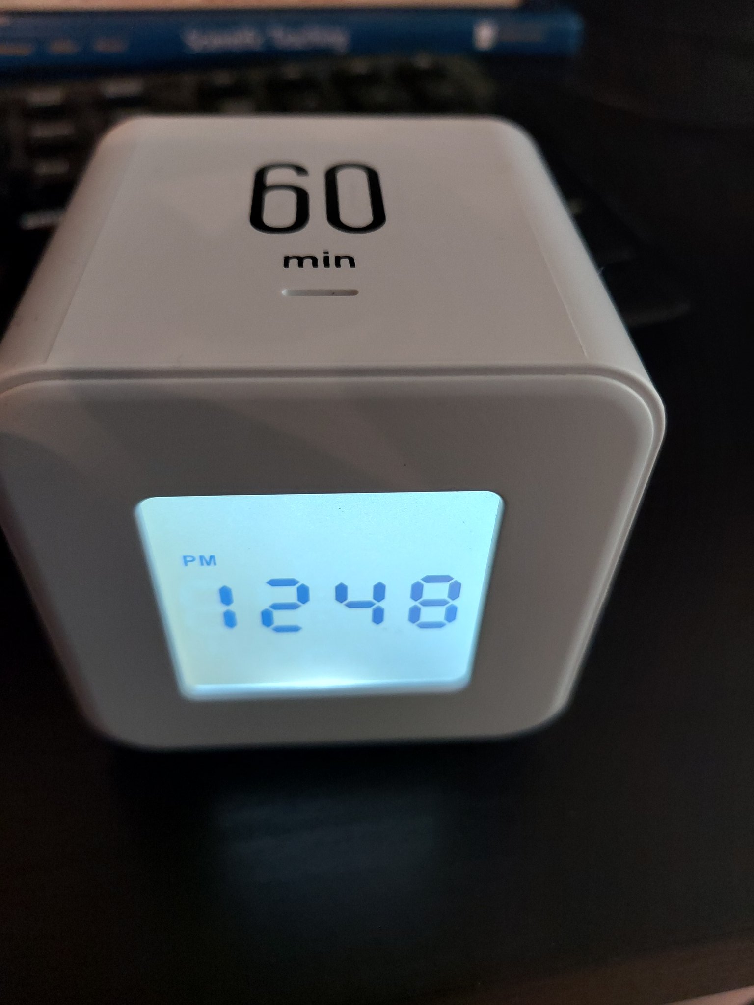 White cube clock/timer with 60 min on top of cube and 12:48 pm displayed on the clock face.